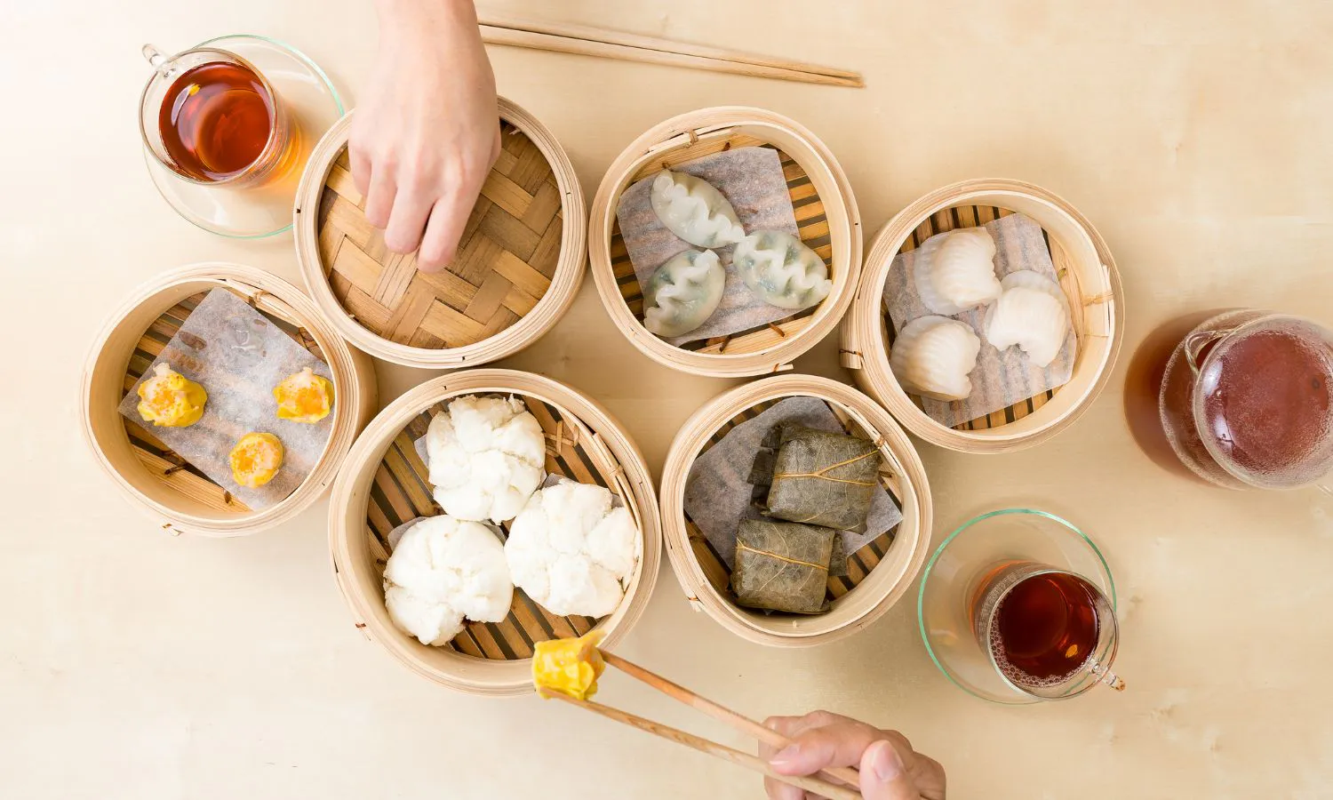Assorted Cantonese dim sum in bamboo steamers with hot tea